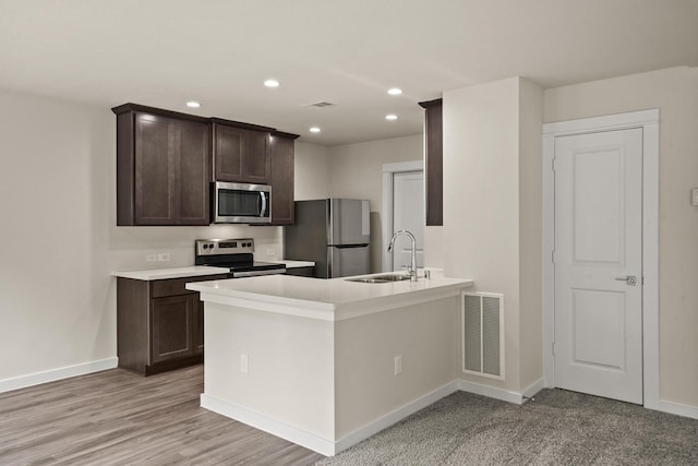 kitchen with sink, light hardwood / wood-style flooring, appliances with stainless steel finishes, dark brown cabinets, and kitchen peninsula