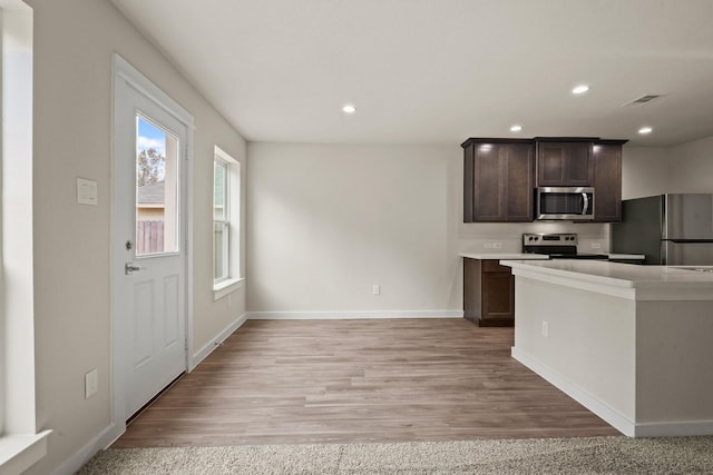 kitchen featuring dark brown cabinetry, stainless steel appliances, and light hardwood / wood-style floors