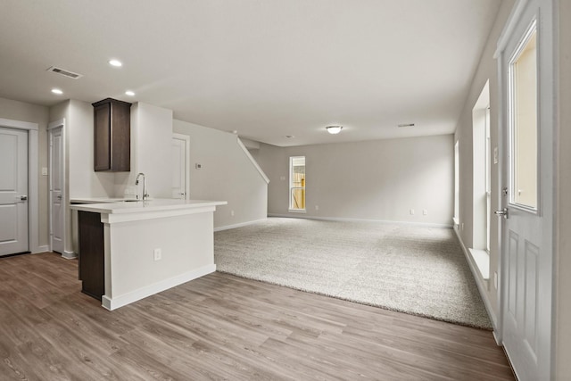 kitchen with light hardwood / wood-style flooring, sink, dark brown cabinets, and kitchen peninsula