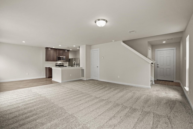 unfurnished living room with sink and carpet