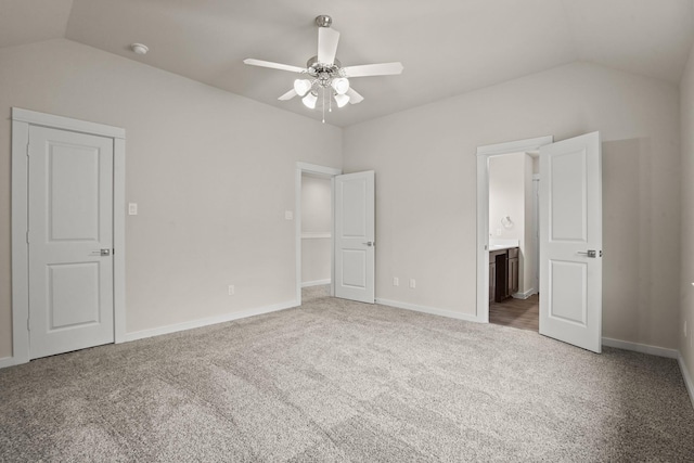 unfurnished bedroom featuring vaulted ceiling, carpet, ceiling fan, and ensuite bath