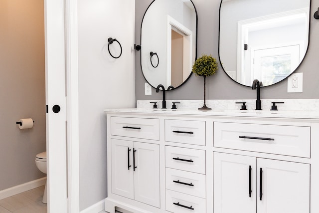 bathroom with toilet, double sink, and large vanity