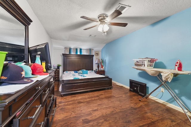 bedroom featuring dark hardwood / wood-style flooring, ceiling fan, and a textured ceiling