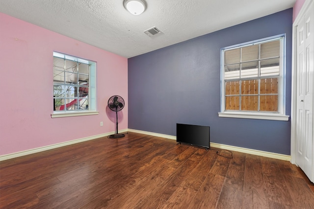 spare room with a textured ceiling and dark wood-type flooring