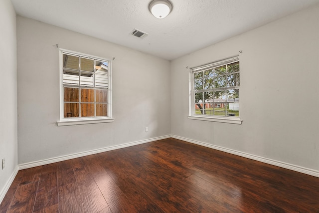 unfurnished room featuring a textured ceiling and dark hardwood / wood-style flooring