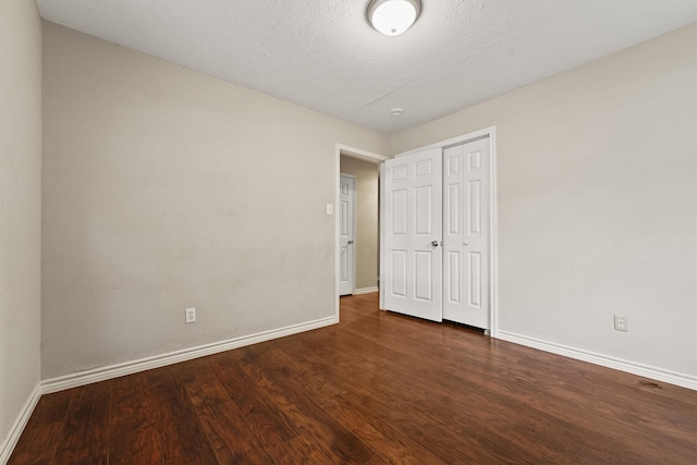 unfurnished bedroom with a closet, dark wood-type flooring, and a textured ceiling