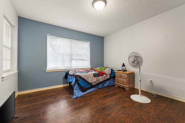 bedroom with multiple windows, a textured ceiling, and dark hardwood / wood-style flooring