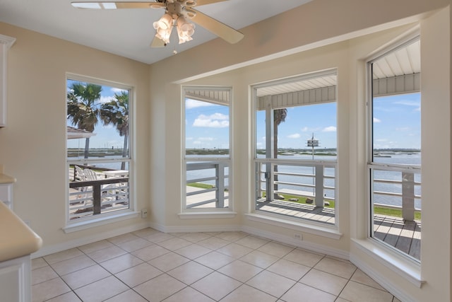 interior space featuring a wealth of natural light, a water view, and ceiling fan