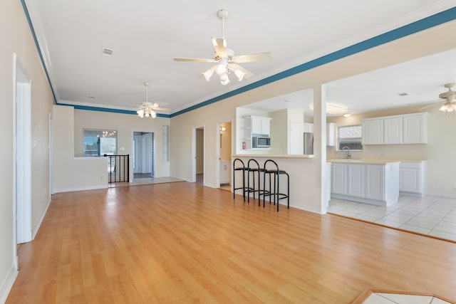 unfurnished living room featuring ceiling fan, light hardwood / wood-style flooring, and crown molding