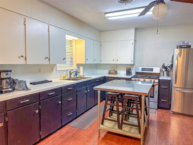 kitchen featuring appliances with stainless steel finishes, wood-type flooring, ceiling fan, and sink