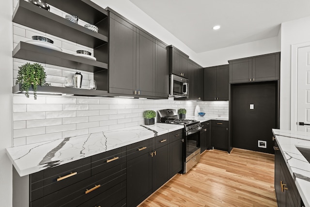 kitchen with backsplash, range with gas cooktop, light stone countertops, and light wood-type flooring