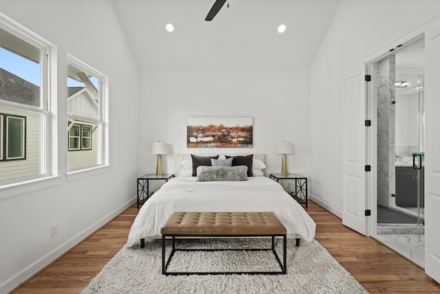 bedroom with connected bathroom, vaulted ceiling, and multiple windows