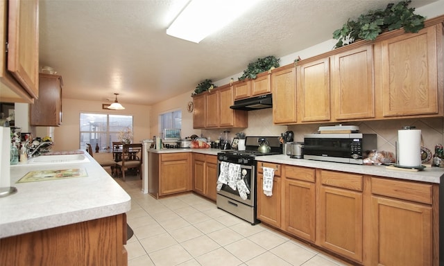 kitchen with backsplash, sink, light tile patterned floors, appliances with stainless steel finishes, and kitchen peninsula