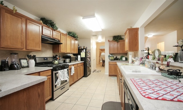 kitchen with gas range, sink, backsplash, black refrigerator, and light tile patterned floors