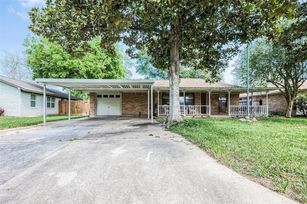 ranch-style home with a porch, a front yard, a carport, and a garage