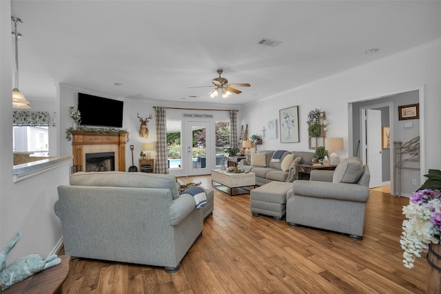 living room with light hardwood / wood-style floors, ceiling fan, french doors, and crown molding