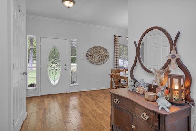 foyer with a healthy amount of sunlight, light hardwood / wood-style floors, and crown molding