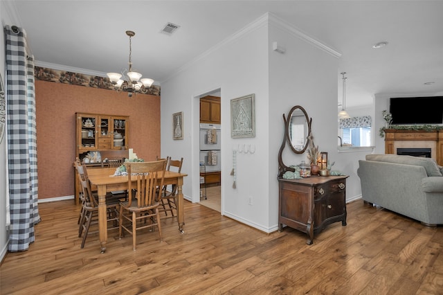 dining area with an inviting chandelier, hardwood / wood-style floors, and ornamental molding