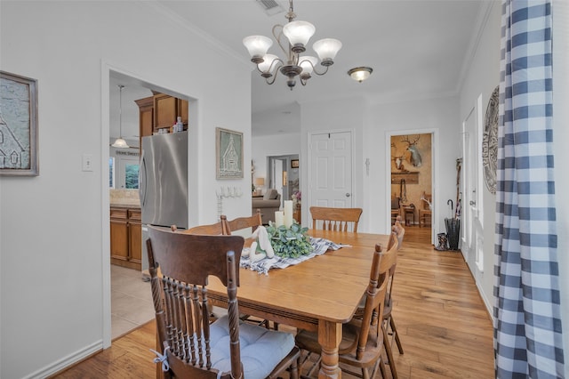 dining area with a notable chandelier, light hardwood / wood-style flooring, and crown molding