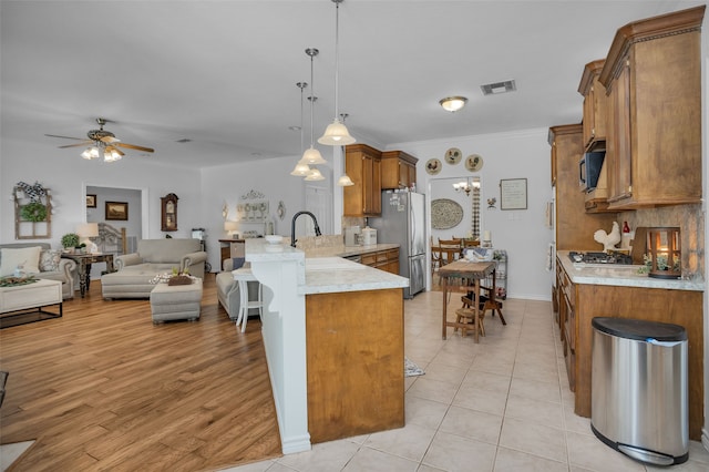 kitchen featuring appliances with stainless steel finishes, pendant lighting, light wood-type flooring, ceiling fan, and sink