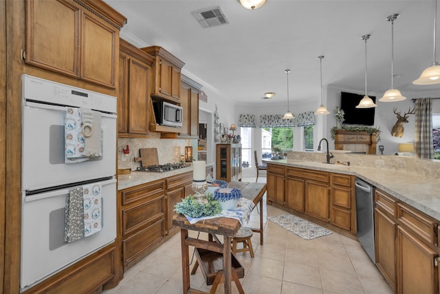 kitchen featuring appliances with stainless steel finishes, hanging light fixtures, tasteful backsplash, and light tile flooring