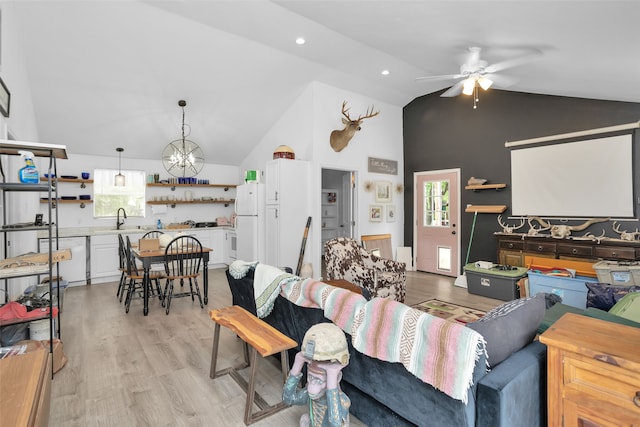 living room with lofted ceiling, light hardwood / wood-style flooring, sink, and ceiling fan with notable chandelier