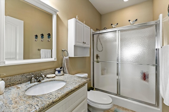 bathroom featuring tile flooring, a shower with door, toilet, and vanity