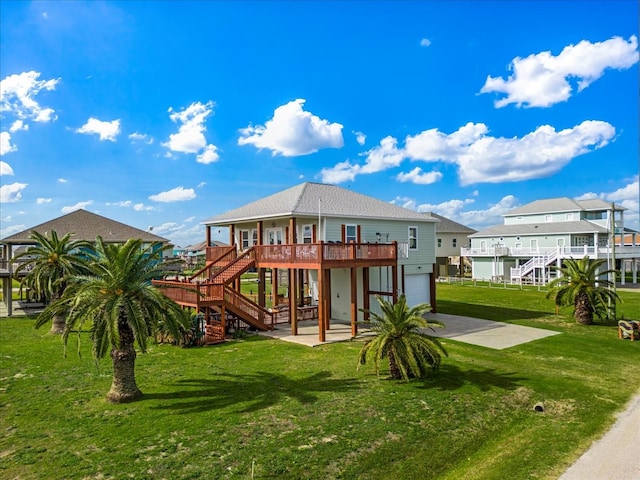 rear view of property with a deck, a patio area, a garage, and a lawn