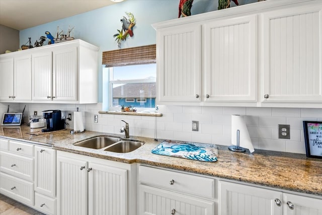 kitchen with light stone countertops, white cabinetry, tasteful backsplash, and sink