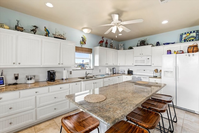 kitchen featuring white cabinets, ceiling fan, white appliances, and a breakfast bar area