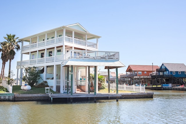 dock area with a balcony, a yard, and a water view