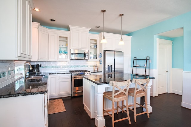 kitchen featuring sink, hanging light fixtures, appliances with stainless steel finishes, dark wood-type flooring, and a center island