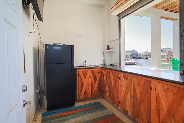 kitchen featuring dark stone counters and black refrigerator