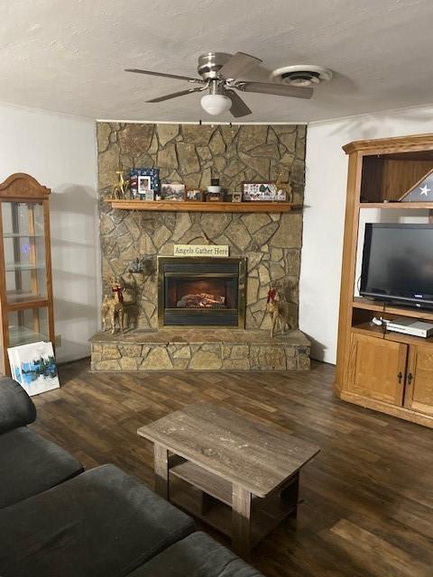 living room with dark hardwood / wood-style flooring, a stone fireplace, and ceiling fan