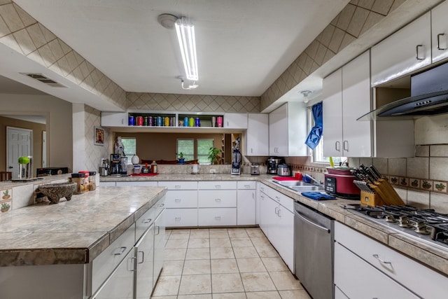 kitchen with tasteful backsplash, white cabinets, appliances with stainless steel finishes, and light tile floors