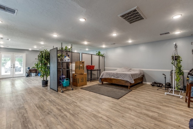 bedroom featuring french doors, a textured ceiling, access to outside, and light hardwood / wood-style flooring