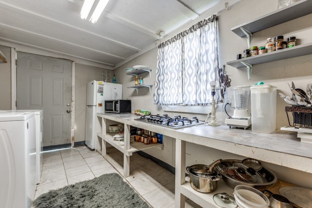 kitchen featuring light tile floors, appliances with stainless steel finishes, and washer / dryer