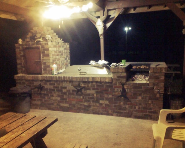 patio terrace at twilight featuring a fireplace and an outdoor kitchen