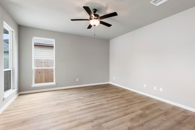 spare room with a textured ceiling, light wood-type flooring, and ceiling fan