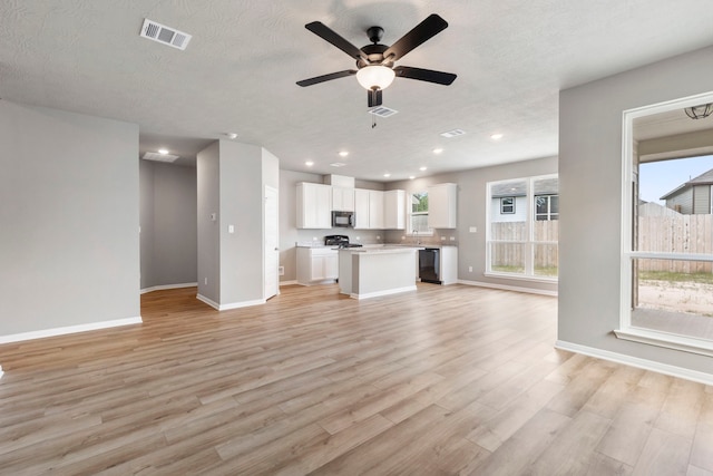 unfurnished living room featuring a textured ceiling, light wood-type flooring, and ceiling fan