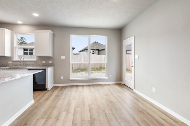 kitchen featuring dishwasher, white cabinets, light wood-type flooring, and a wealth of natural light