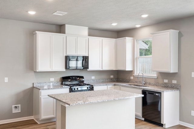 kitchen featuring a center island, black appliances, sink, and white cabinets