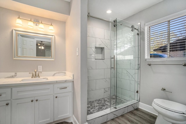 bathroom with ceiling fan, hardwood / wood-style floors, toilet, vanity, and a shower with shower door