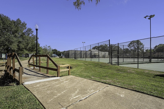 view of home's community with a yard and tennis court