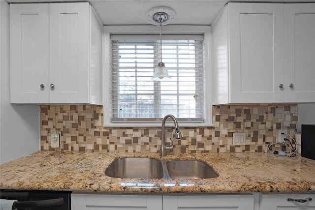 kitchen featuring decorative light fixtures, white cabinetry, sink, and light stone counters