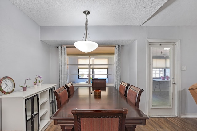 dining room with a textured ceiling, dark wood-type flooring, and a wealth of natural light