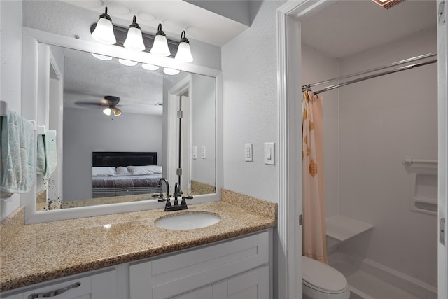 bathroom featuring toilet, vanity with extensive cabinet space, ceiling fan, a textured ceiling, and walk in shower