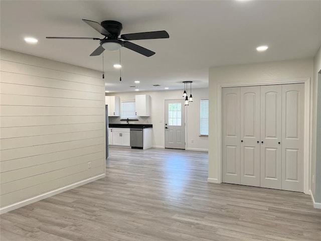 kitchen with appliances with stainless steel finishes, pendant lighting, light wood-type flooring, ceiling fan, and white cabinets