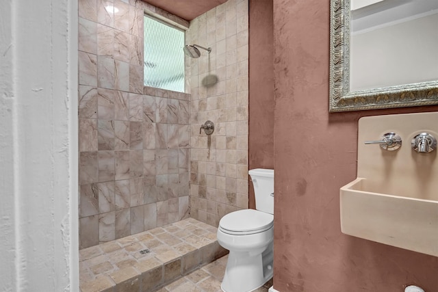 bathroom featuring toilet, tile flooring, sink, and tiled shower