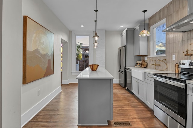 kitchen featuring wall chimney exhaust hood, gray cabinets, dark hardwood / wood-style flooring, and stainless steel appliances